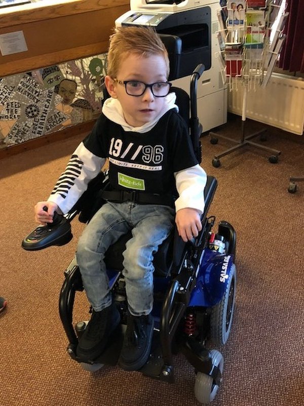 Logan first came to Whizz Kidz five years ago Logan in his wheelchair, when he was younger. He;s wearing a black and white top, glasses and jeans.