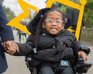 A young wheelchair user in her powered chair holding her mother's hand
